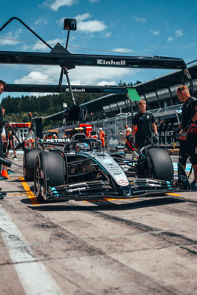 Ένα αυτοκίνητο Mercedes-AMG Formula 1 είναι στη λωρίδα pit, περιτριγυρισμένο από μέλη της ομάδας κάτω από τη δομή γκαράζ της Einhell.